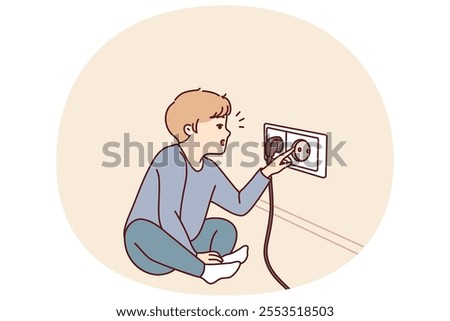 Small boy sticks fingers into socket, playing with electrical equipment and risking electric shock. Preschool child with curiosity pulls fingers to electrical socket and needs attention of parents