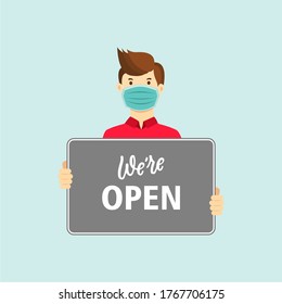 Small business owner wearing face mask holding sign we are open. support local business reopening shop concept. coronavirus covid-19 prevention in new normal