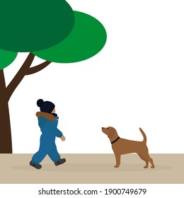 A small child in a warm overalls goes to the dog in the park