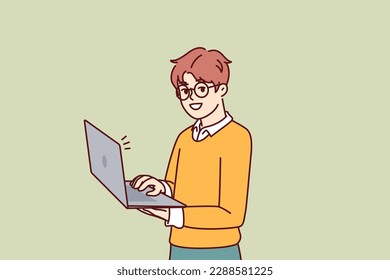 Smart little boy with open laptop for preparing homework assigned from school stands and looks at camera. Schoolboy in casual wear holding laptop using internet and learning software development 