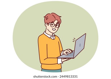 Smart little boy with open laptop for preparing homework assigned from school stands and looks at camera. Schoolboy in casual wear holding laptop using internet and learning software development