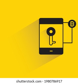 smartphone y clave privada de bitcoin con sombra sobre fondo amarillo
