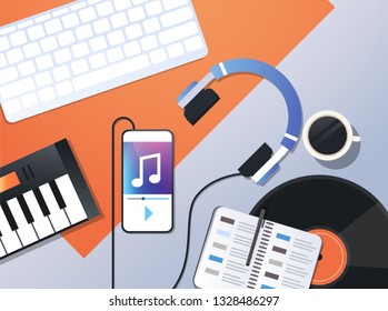 smartphone playing music via headphones audio mobile app concept top angle view workplace desktop with keyboard headphones piano office stuff horizontal