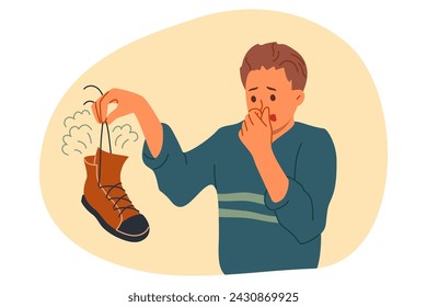 Smelly shoe in hands of man suffering from bad odor and symptoms of foot mycosis. Guy with smelly feet needs help from dermatologist or shoe disinfectant to get rid of stinky bacteria.