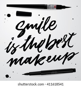 "Smile is the best makeup". Inspirational quote handwritten with black ink and brush, custom lettering for poster, t-shirt and card. Calligraphy isolated on grey background. Vector Illustration.