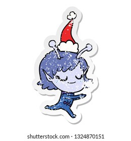 smiling alien girl hand drawn distressed sticker cartoon of a running wearing santa hat
