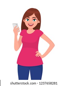 Smiling beautiful young woman holding smart phone while holding hand on hip and standing against white background. Modern lifestyle and communication concept illustration in vector cartoon flat style.