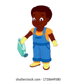 Smiling boy dressed in a shirt, denim overall, watertight boots and gloves holds a watering can in the right hand. Concept of a child helping out with the work around the house or in the garden.