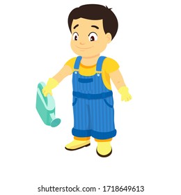 Smiling boy dressed in a shirt, denim overall, watertight boots and gloves holds a watering can in the right hand. Concept of a child helping out with the work around the house or in the garden.