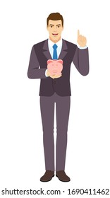 Smiling Businessman holding a piggy bank and pointing up. Portrait of Businessman in a flat style. Vector illustration.