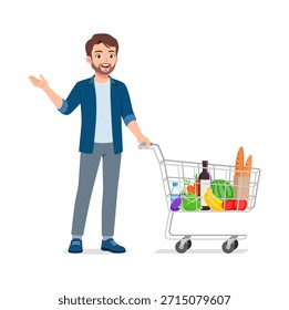 Hombre caucásico sonriente que empuja un Carrito de compras lleno del comestible que mira feliz y amistoso que hace gestos con su mano