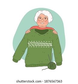 Smiling ederly woman grandmother in glasses showing warm knitted green sweater