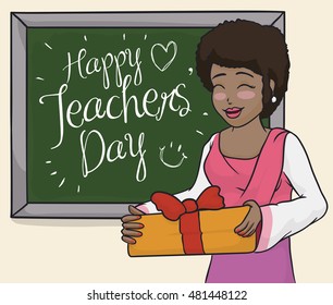 Smiling female educator celebrating with her students Teachers' Day with a big gift and greeting message in the chalkboard.