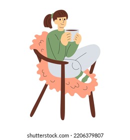 Smiling girl in warm clothes sits in armchair, holds a cup of warm drink. Cosy hygge aesthetics. Female character. Flat hand-drawn vector  