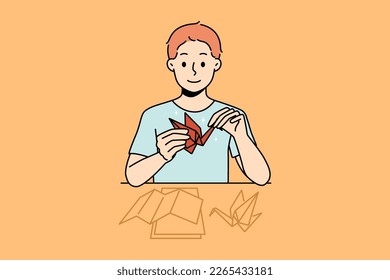 Smiling little boy sit at desk make origami. Happy kid enjoy hobby activity making birds from paper. Vector illustration. 