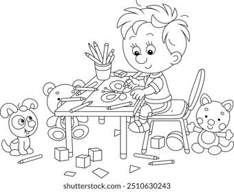 Smiling little boy sitting at his table and drawing with pencils a funny picture, black and white vector cartoon illustration for a coloring book