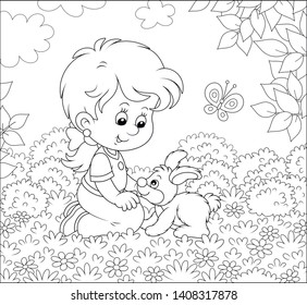 Smiling little girl playing with her small bunny among flowers on a lawn on a summer day, black and white vector illustration in a cartoon style for a coloring book