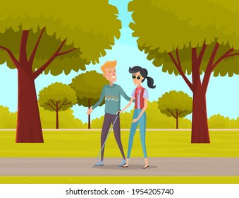 Smiling male volunteer helping and supporting blind woman, people walking along path in city park