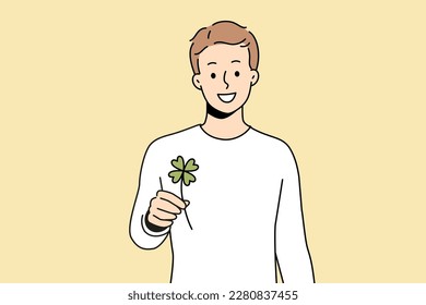 Smiling man holding clover with four leaves feeling lucky. Happy guy with trefoil in hands excited with good luck or fate. Superstition. Vector illustration. 