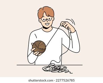 Smiling man sit at table with thread in hands. Happy male in glasses weaving or yarning. Hobby and leisure activity. Vector illustration. 