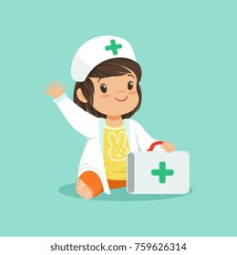 Smiling toddler girl holding medical suitcase and waving hand. Cartoon baby character wearing in doctor s coat and hat