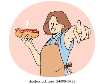 Smiling woman in apron holding hot dog point at screen. Happy waitress with fastfood in hands show at camera with finger. Vector illustration.