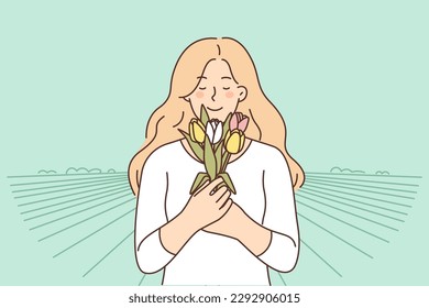 Mujer sonriente con ramo de flores en la plantación del campo para el concepto de cultivo y tulipanes en crecimiento. Chica feliz con los ojos cerrados insinúa las flores se regocijan por la llegada de la primavera 