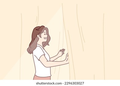 Smiling woman looks out window opening curtains and enjoying rays of summer morning sun. Girl opens curtains rejoicing at new sunny day after waking up in morning or dreams of going for walk
