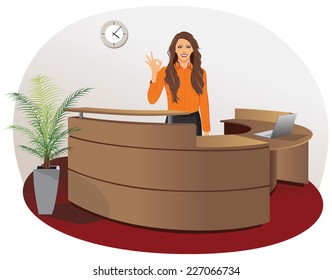 Smiling woman at office reception with okay gesture