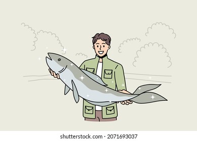 Smiling young fisherman hold big fish proud of good haul or hunt. Happy man in green costume satisfied with successful fishing. Hobby, fishery concept. Flat vector illustration, cartoon character. 