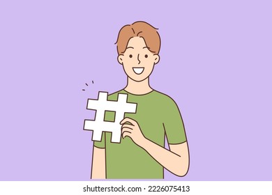 Smiling young man holding hashtag sign. Happy millennial guy with gesture in hands. Vector illustration. 
