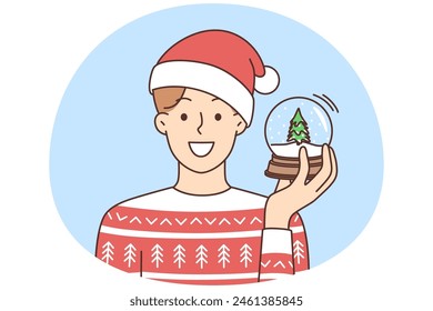 Smiling young man in winter sweater and santa hat holding glass snow ball. Happy guy have fun celebrate new year holidays. Vector illustration.