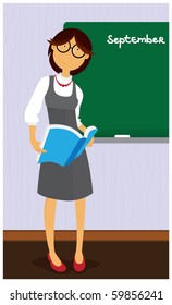 Smiling young teacher standing in front of a blackboard.