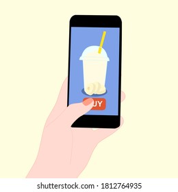 The smoothie juice in the glass cup with fruit (banana)​ beside. They are in online purchase with mobile app. A cold soft drink for summer.