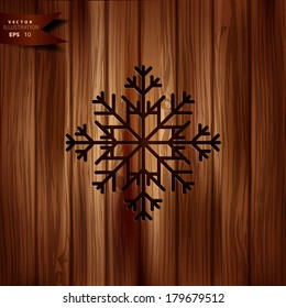 Snowflake icon. Wooden background.