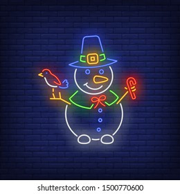 Snowman wearing witch hat, holding bird and candy cane neon sign. Winter season, Christmas design. Night bright neon sign, colorful billboard, light banner. Vector illustration in neon style.