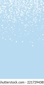 Snowy christmas background. Subtle flying snow flakes and stars on light blue winter backdrop. Delicate sweet snowy christmas. Vertical vector illustration.
