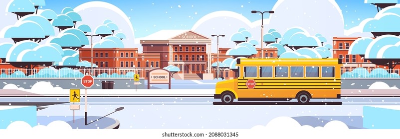 snowy school building empty front yard with trees road and school buswinter cityscape background