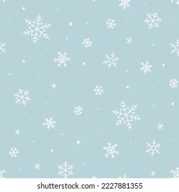 Snowy winter seamless pattern of hand drawn snow flakes on light blue background