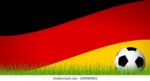 soccer ball lying in the grass in front of german flag