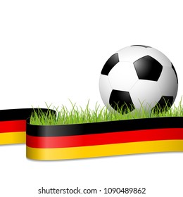 soccer ball lying in the grass with german colors banner