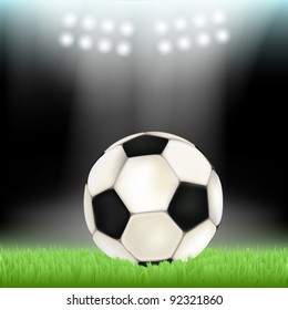 Soccer ball on stadium field grass, illuminated by floodlights