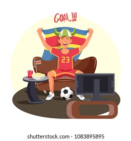 Soccer fan celebrating goal at home watching tv and holding flag. Football team supporter with soda and popcorn watching game.