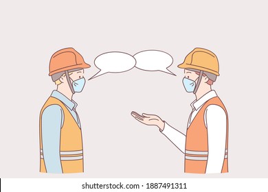 Social distance at work during pandemic concept. Men workers in medical protective face masks standing and keeping distance during talking together on work in factory to prevent Covid-19 virus 