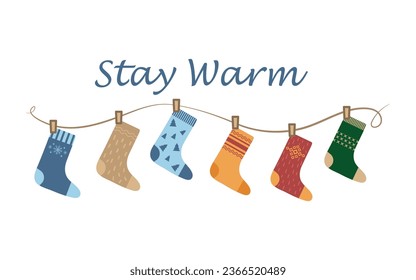 Socks on a rope with the inscription stay warm. Elements of clothing with cute Christmas patterns dry a collection of socks on a rope. Cozy winter accessories for winter and autumn. Vector illustratio