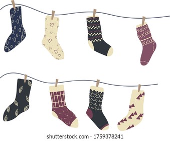 Socks with ornaments and patterns are dried on a rope with clothespins.