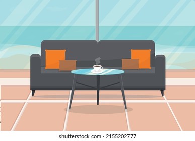 a sofa and a table with a cup of coffee stands in a room overlooking the sea