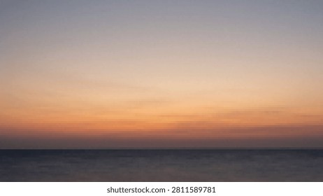 Soft gradient sky blending orange and purple hues at dusk over tranquil ocean waves