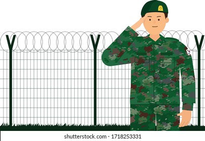 The soldier is saluting in front of the fence.