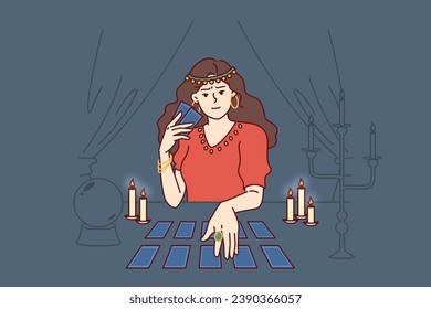 Soothsayer woman holds tarot cards predicting future and performing magical ritual to bewitch betrothed. Soothsayer girl sits at table with candles and mysterious ball for communicating with spirits